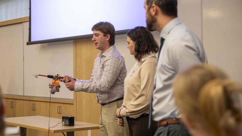 Male student showcases adaptive fishing rod.